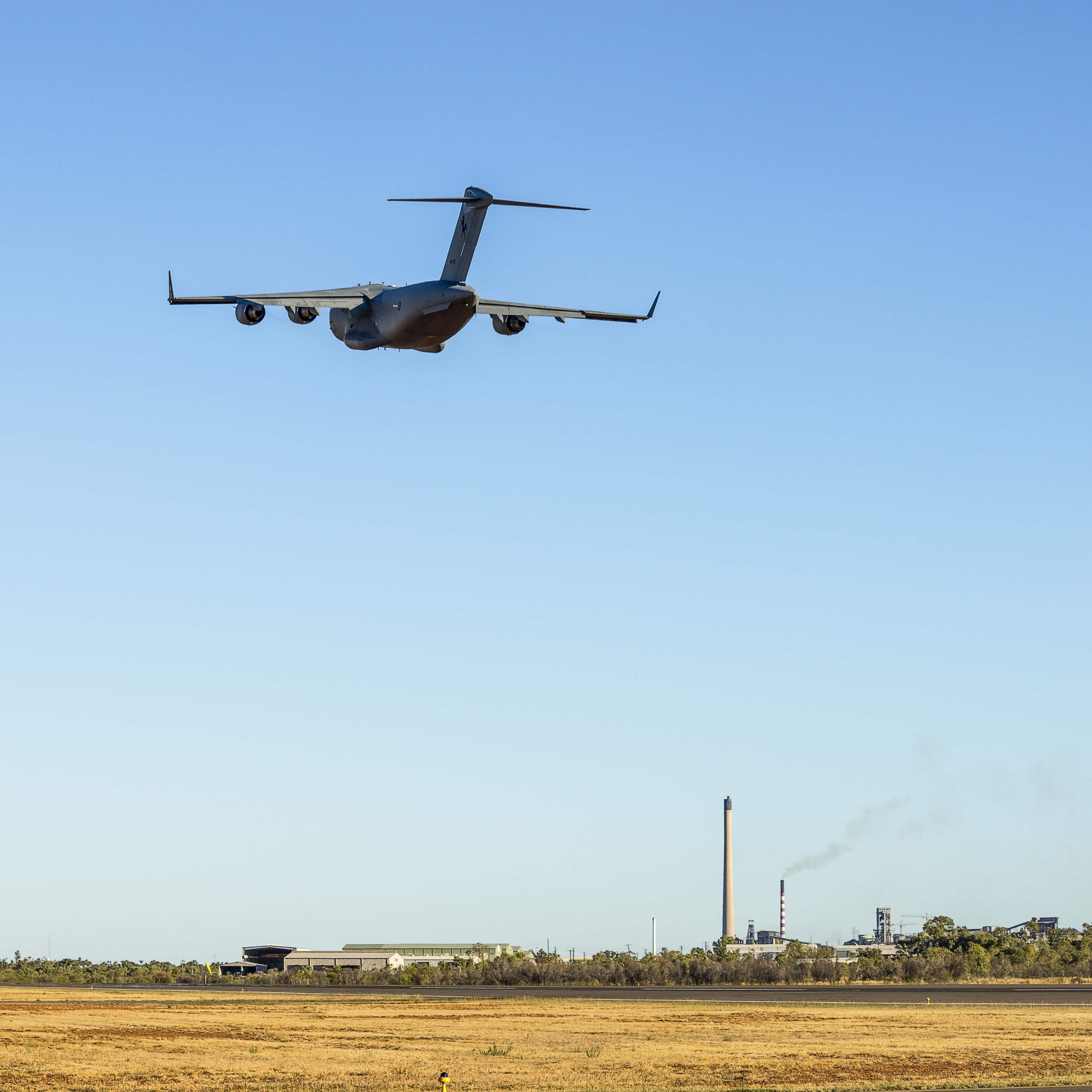 RAAF C-17 climbing out over the Mount Isa mine stacks